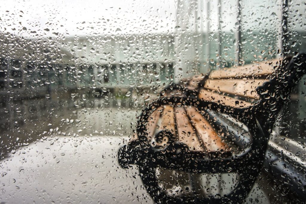 Rain-soaked window with a view of a bench outside in Fatih, Istanbul, Turkey.